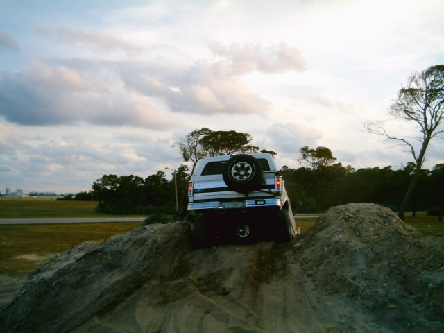 White SUV with spare tire on rear, climbing a dirt mound