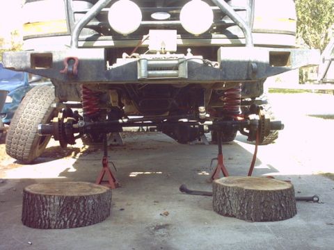 1994 Ford Bronco - The front suspension and undercarriage of a lifted truck are visible, supported by jack stands.