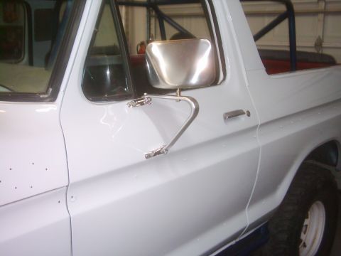 1978 Ford Bronco - Close-up of the driver's side of a white Ford Bronco, showing the door and side mirror.