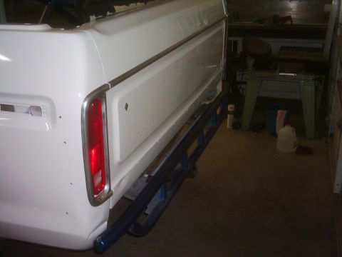 1978 Ford Bronco - Rear view of a white pickup truck with a blue step bar and chrome trim on the tailgate.