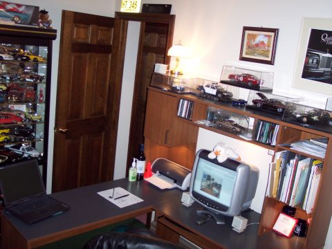2001 Ford Crown Victoria - A collection of model cars is displayed on shelves above a desk in an office setting.