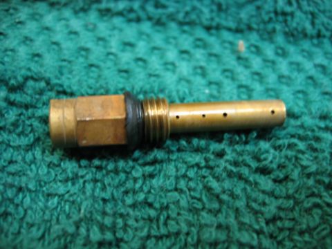 1985 Ford LTD Crown Victoria - A close-up view of a brass carburetor jet with an O-ring and multiple small holes.