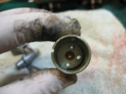 1985 Ford LTD Crown Victoria - A gloved hand holds a carburetor float bowl, showing internal components and a dirty exterior.