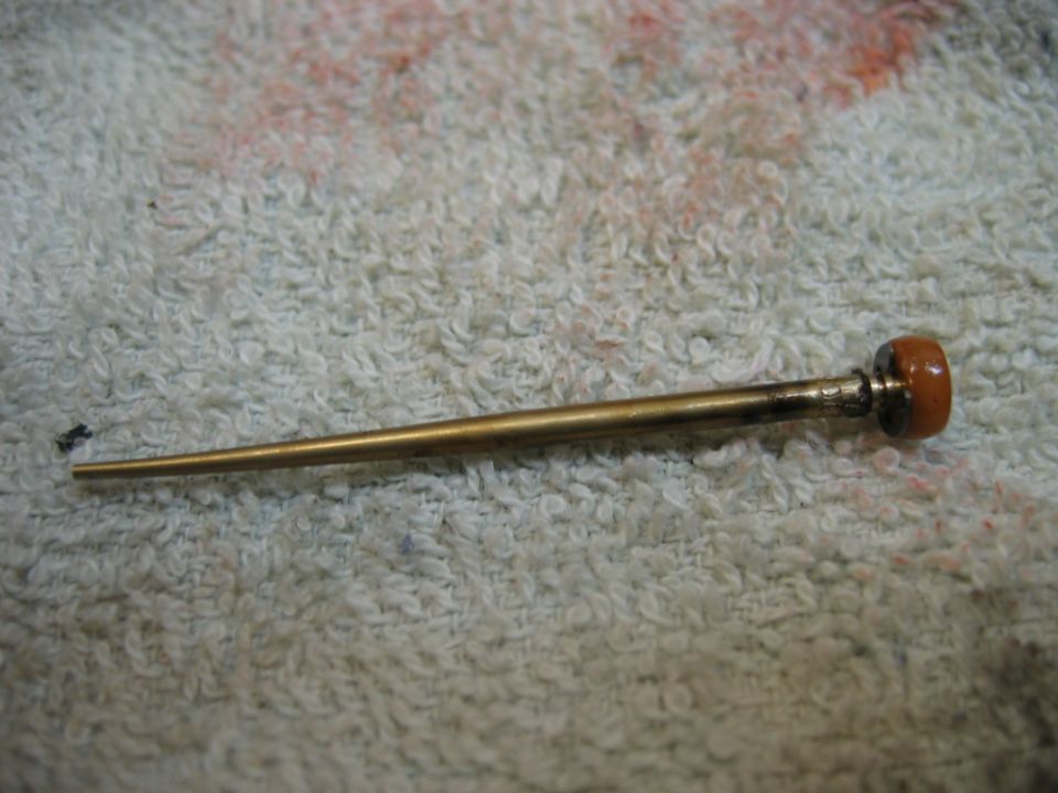 Carburetor needle valve with brown tip on textured surface