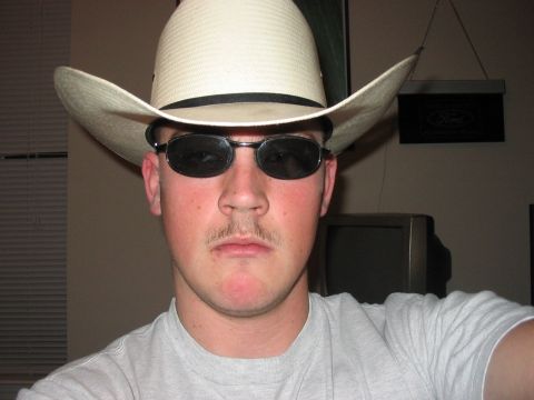1988 Ford Bronco - A man in a cowboy hat and sunglasses poses for a photo, with a Ford logo visible on the wall behind him.