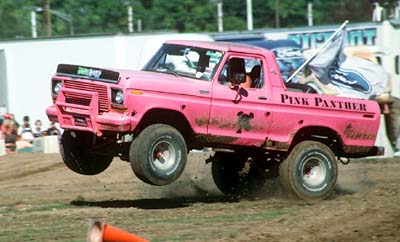 1978 Ford Bronco - Pink Panther pickup truck airborne during an event, showing custom paint and graphics.