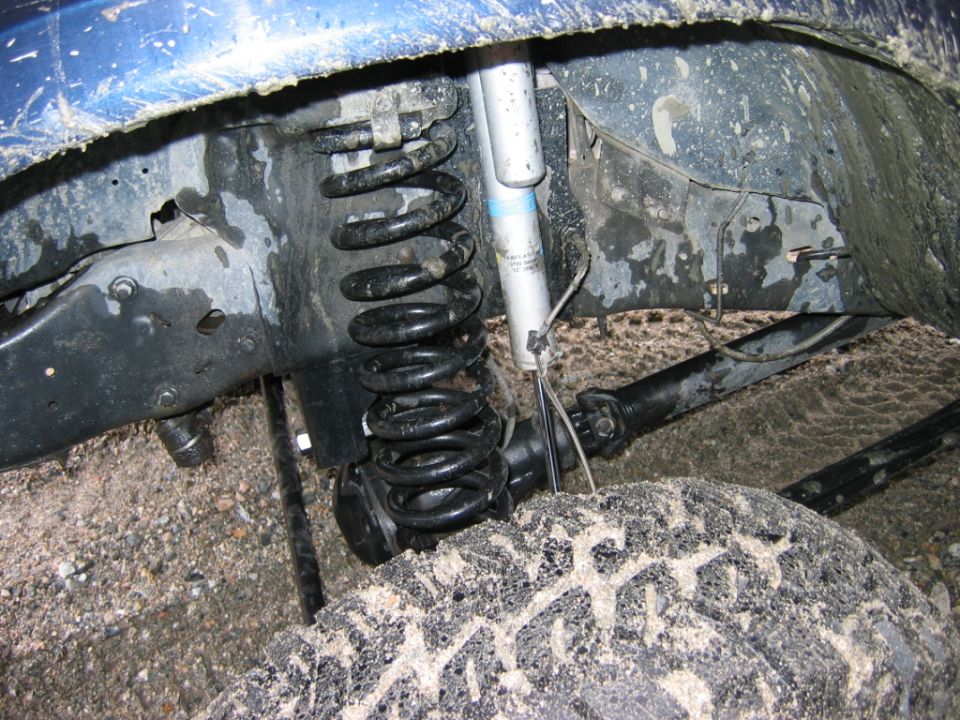Undercarriage view of coil spring, shock absorber and driveshaft on a blue-framed vehicle