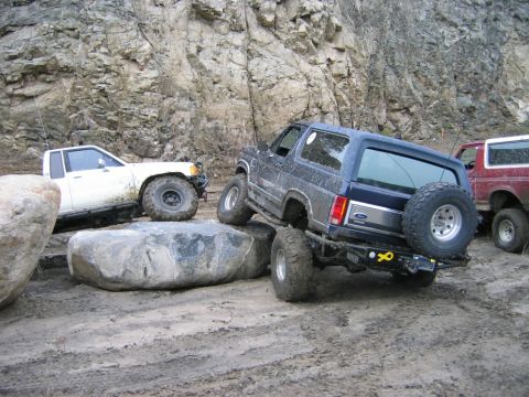 1985 Ford Bronco - A blue 1985 Ford Bronco tackles a rocky trail with other off-road vehicles present.
