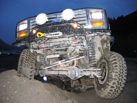 1985 Ford Bronco - This modified Ford Bronco is covered in mud, equipped with a winch and auxiliary lights for off-road use.