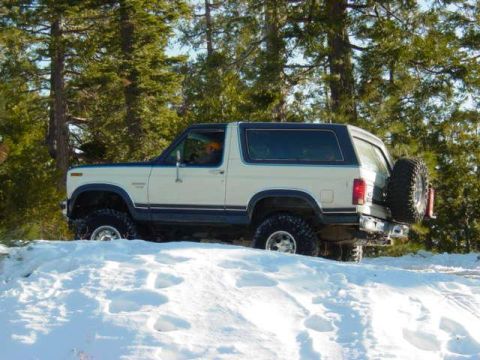 1986 Ford Bronco - White and blue 1986 Ford Bronco navigates a snowy terrain.