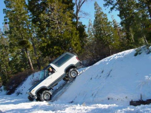 1986 Ford Bronco - A 1986 Ford Bronco navigates a snowy hill, demonstrating its off-road capability.