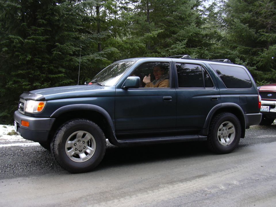 Dark green 1996 Toyota 4Runner side view with driver giving thumbs up