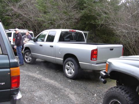1991 Ford Bronco - A silver pickup truck is parked on a gravel road with other vehicles nearby.