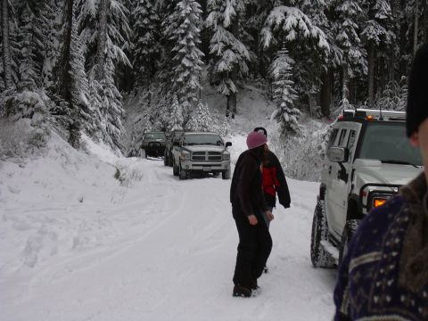 1991 Ford Bronco - A convoy of vehicles navigates a snowy forest road during winter.
