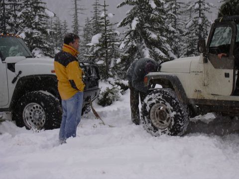 1991 Ford Bronco - Two off-road vehicles are stuck in the snow during a winter outing, with people attempting to free them.
