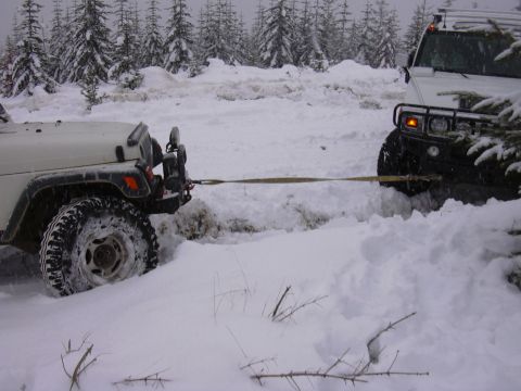 1991 Ford Bronco - Two off-road vehicles are stuck in deep snow, with one vehicle attempting to tow the other out.