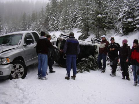 1991 Ford Bronco - A group of people stand around a crashed Jeep and a damaged pickup truck in a snowy, wooded area.