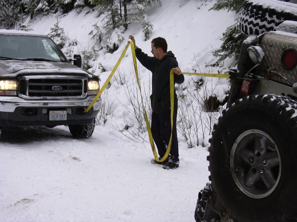Ford truck and Jeep in snow, guy holding tow strap