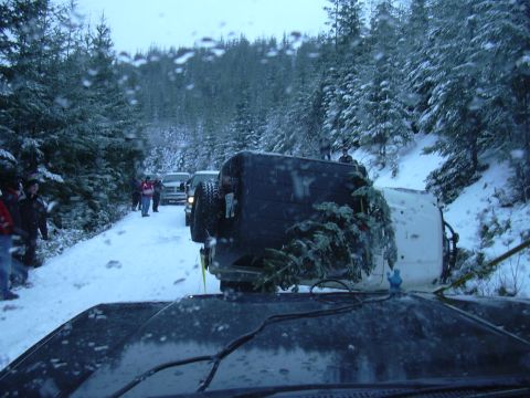 1991 Ford Bronco - Several vehicles are stopped on a snow-covered road in a wooded area, with one vehicle overturned.
