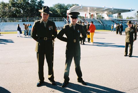 1994 Ford Bronco - Two uniformed military personnel stand at attention outdoors with spectators and a grandstand visible.