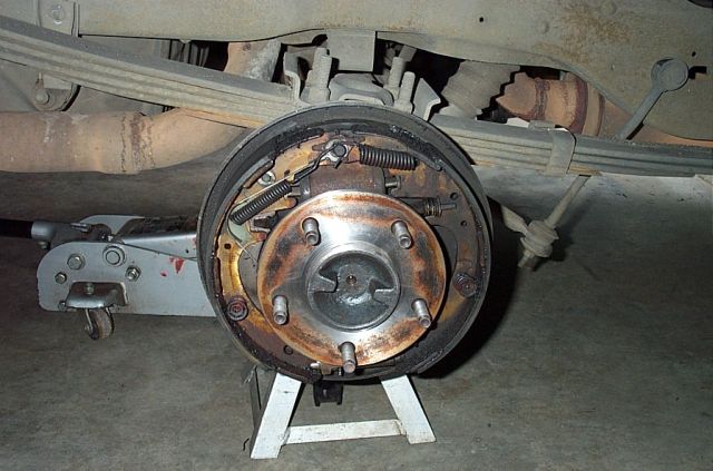 Rear drum brake assembly exposed showing shoes, springs and hub on a vehicle on jack stand