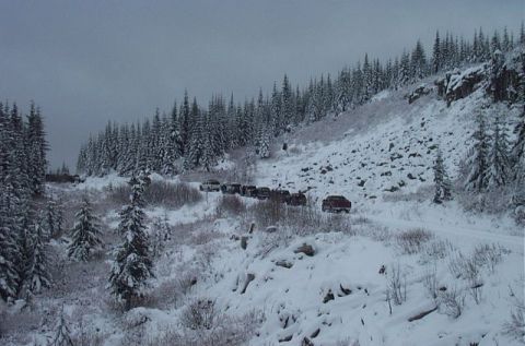 1995 Ford Bronco - A group of vehicles navigates a snowy mountain pass under an overcast sky.