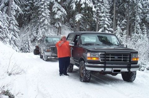 1995 Ford Bronco - A group of SUVs, including a 1995 Ford Bronco, navigate a snowy forest road.