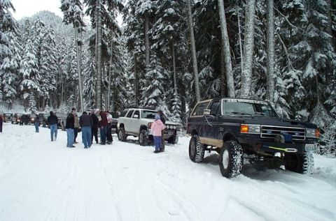 1995 Ford Bronco - Several 4x4 vehicles and people gathered in a snowy forest during an event.