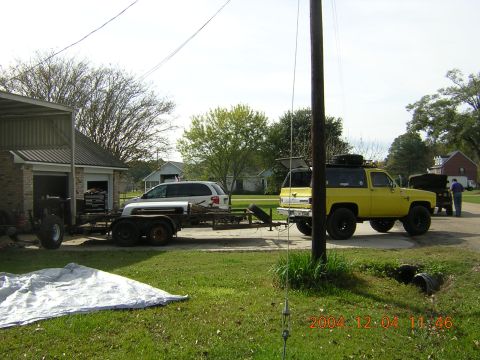 1984 Chevrolet Blazer - A yellow SUV is parked on a residential street, towing a trailer behind it.
