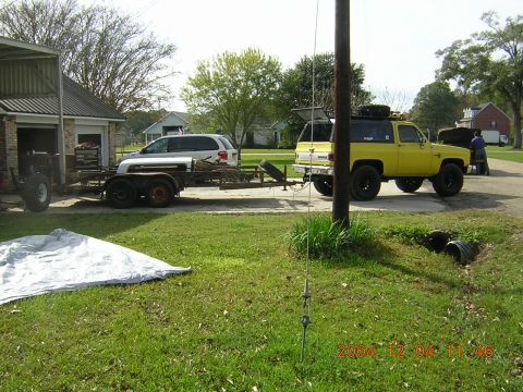 1984 Chevrolet Blazer - A yellow 1984 Chevrolet Blazer is hitched to a trailer carrying a white SUV, parked in a driveway.
