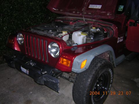 1984 Chevrolet Blazer - A red Jeep Wrangler is shown with its hood open, revealing the engine bay and a damaged front bumper.