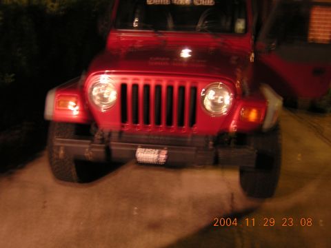 1984 Chevrolet Blazer - A red Jeep Wrangler is parked on a paved surface at night, with its front grille and headlights clearly visible.