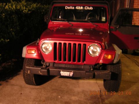 1984 Chevrolet Blazer - A red Jeep Wrangler is parked in front of a brick building, with a 'Delta 4x4 Club' sticker on the windshield.