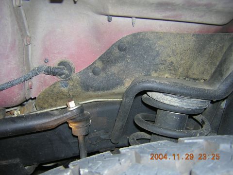 1984 Chevrolet Blazer - Close-up view of the suspension system of a red vehicle, showing a coil spring and other mechanical parts.
