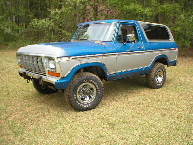 Blue and white late-70s Ford Bronco on Mastercraft mud tires parked on grass