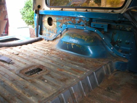 1978 Ford Bronco - Stripped rear cargo area of a blue Ford Bronco during restoration, with the ribbed steel floor pan bare and surface-rusted and old paint fl…