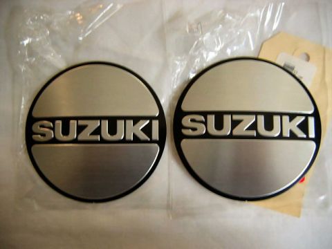 1985 Ford LTD Crown Victoria - Pair of Suzuki emblems, likely for a vehicle's wheel or body, prominent branding.