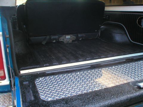 1978 Ford Bronco - Interior rear cargo area of a blue Ford Bronco shot through the open tailgate, with the floor, wheel wells and tailgate top freshly coated…