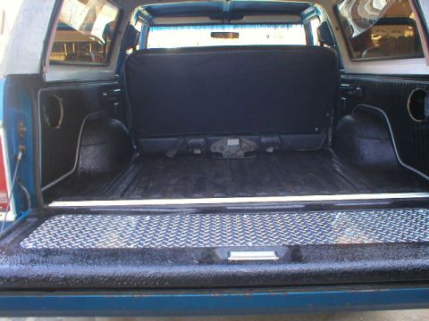 1978 Ford Bronco - Rear cargo area of a blue SUV shot through the open tailgate, with fresh black textured bedliner coating sprayed over the floor, tailgate a…
