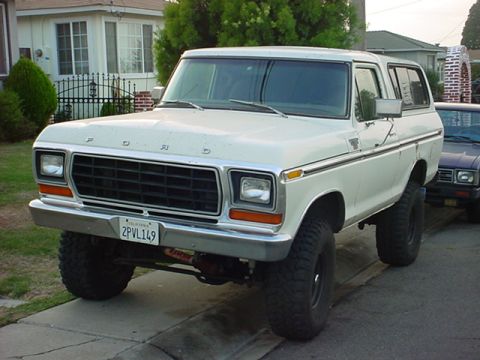 1978 Ford Bronco - A white 1978 Ford Bronco is parked on a street, showing its lifted suspension and off-road tires.