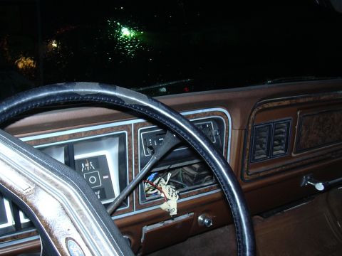 1978 Ford Bronco - The interior of a 1978 Ford Bronco shows its dashboard with wood grain accents and a worn steering wheel.