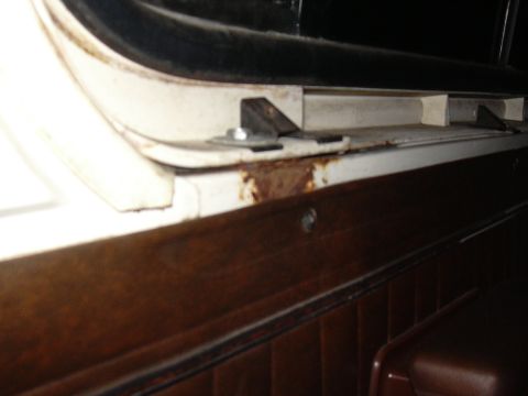 1978 Ford Bronco - The interior door panel shows wood-grain trim and visible rust on the upper frame.