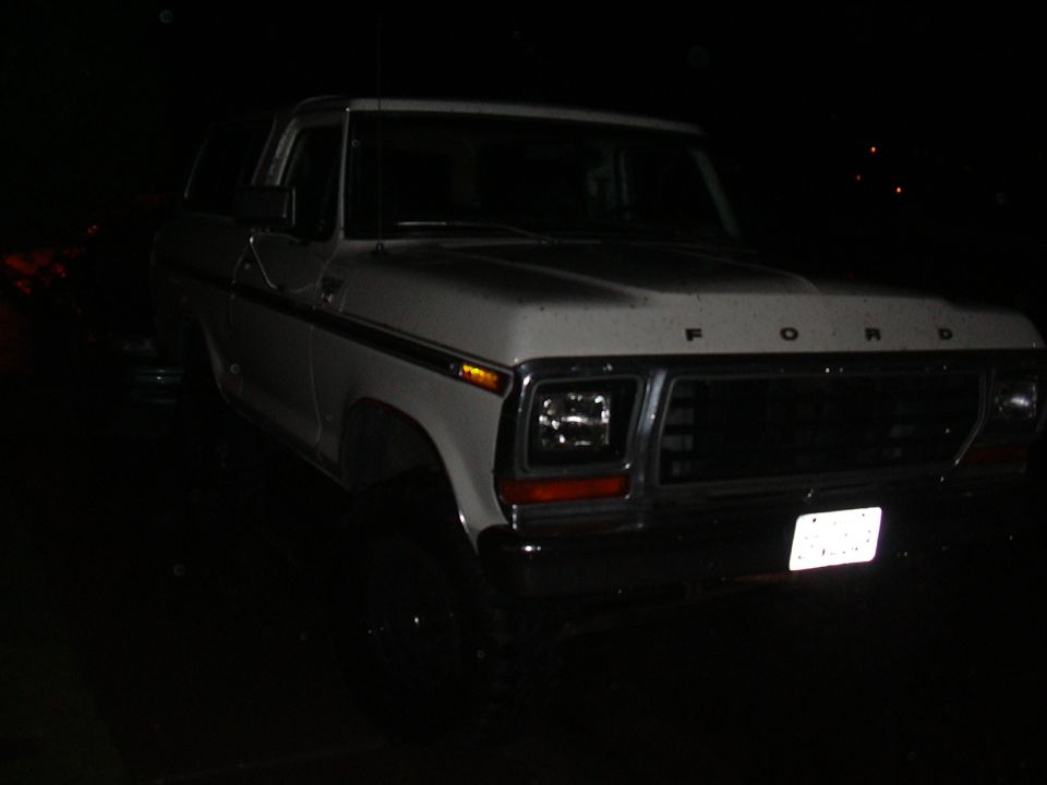 White 1978 Ford Bronco with chrome bumper and grille, seen at night
