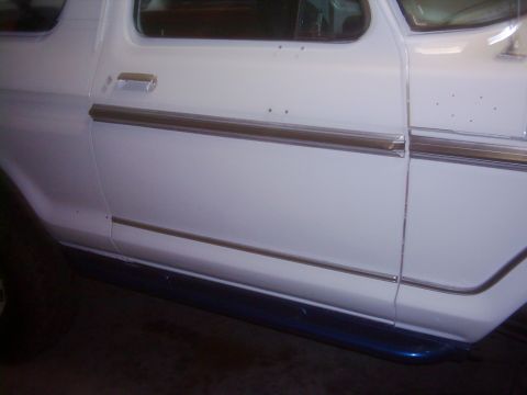 1978 Ford Bronco - Close-up of a white SUV's side panel, showing door handle and trim details.