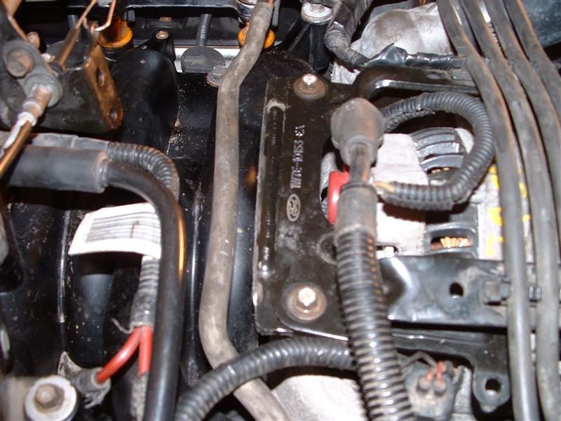 Close-up of engine bay with wiring, hoses, and alternator visible. Part number 13-5514-01M stamped on bracket