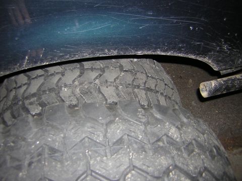 1995 Ford Bronco - Close-up view of a vehicle's tire and fender well, showing wear and tear.