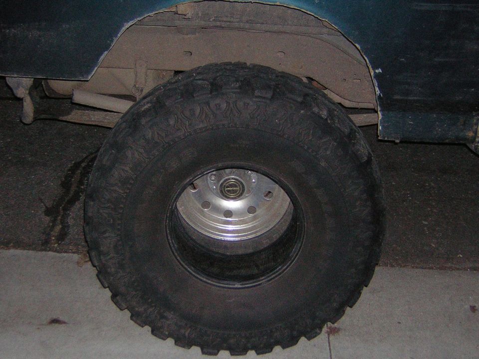 Close-up of a large off-road tire on a vehicle, showing the wheel hub and part of the fender