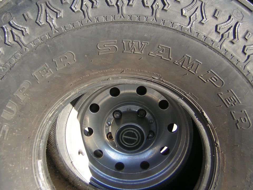 Close-up of a Super Swamper tire on a silver wheel with five lug nuts