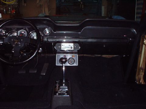 1967 Ford Mustang - The interior of a 1967 Ford Mustang shows a black dashboard with gauges and an aftermarket radio.