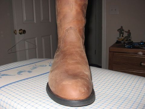 1988 Ford Bronco - A close-up view of a brown leather cowboy boot rests on a surface, with household items visible behind it.